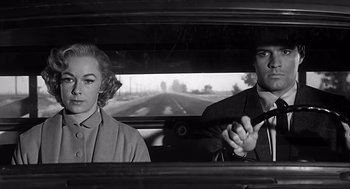 Movie still from “Psycho” (1960), directed by Alfred Hitchcock – A man and a woman sitting in the back seat of a car; Medium shot, Low angle