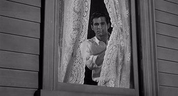 Movie still from “Psycho” (1960), directed by Alfred Hitchcock – A black and white photo of a man looking out of a window; Medium shot, Low angle