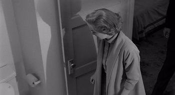 Movie still from “Psycho” (1960), directed by Alfred Hitchcock – A black and white photo of a woman standing in front of an open door; Medium shot, Over the shoulder angle