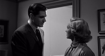 Movie still from “Psycho” (1960), directed by Alfred Hitchcock – A man and a woman standing next to each other in front of a window; Medium shot, Low angle