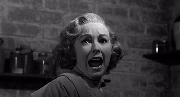 Movie still from “Psycho” (1960), directed by Alfred Hitchcock – An older woman with a surprised look on her face; Close Up shot, Low angle