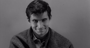 Movie still from “Psycho” (1960), directed by Alfred Hitchcock – Black and white photograph of a man smiling for the camera; Close Up shot, High angle