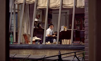 Movie still from “Rear Window” (1954), directed by Alfred Hitchcock – A man sitting in front of an open window; Wide shot, High angle