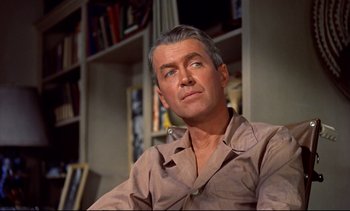 Movie still from “Rear Window” (1954), directed by Alfred Hitchcock – An older man sitting in front of bookshelves; Close Up shot, Low angle