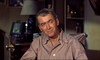 Movie still from “Rear Window” (1954), directed by Alfred Hitchcock – An older man wearing a brown shirt sitting in a chair; Close Up shot, Over the shoulder angle