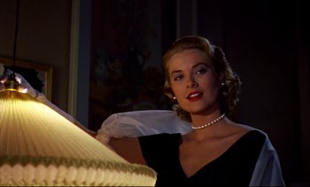 Movie still from “Rear Window” (1954), directed by Alfred Hitchcock – A woman in a black dress and a pearl necklace; Close Up shot, Low angle