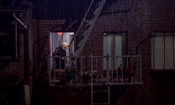 Movie still from “Rear Window” (1954), directed by Alfred Hitchcock – A man standing on a porch looking out the window; Wide shot, High angle