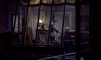 Movie still from “Rear Window” (1954), directed by Alfred Hitchcock – A man standing in front of an open window; Wide shot, High angle