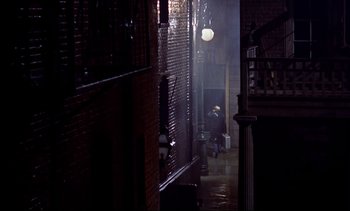 Movie still from “Rear Window” (1954), directed by Alfred Hitchcock – A man walking down a street in the rain; Extreme Wide shot, High angle