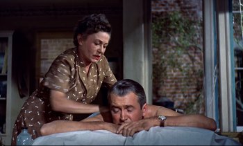 Movie still from “Rear Window” (1954), directed by Alfred Hitchcock – An older man and a younger woman are getting a massage; Medium shot, High angle