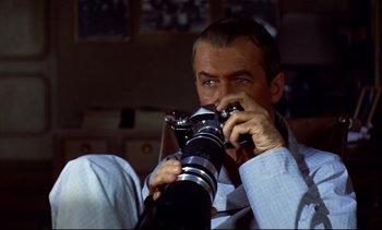 Movie still from “Rear Window” (1954), directed by Alfred Hitchcock – A man holding a camera up to his face; Close Up shot, Over the shoulder angle