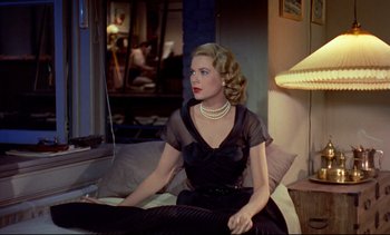 Movie still from “Rear Window” (1954), directed by Alfred Hitchcock – A woman sitting on a couch wearing a black dress; Medium shot, Over the shoulder angle