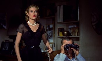 Movie still from “Rear Window” (1954), directed by Alfred Hitchcock – A man and a woman looking through binoculars in a living room; Medium shot, Low angle