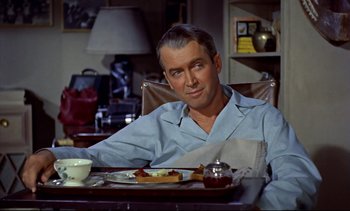 Movie still from “Rear Window” (1954), directed by Alfred Hitchcock – A man sitting at a table with a plate of food; Medium shot, Over the shoulder angle