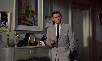 Movie still from “Rear Window” (1954), directed by Alfred Hitchcock – A man in a suit and tie holding a glass of wine; Medium shot, Low angle