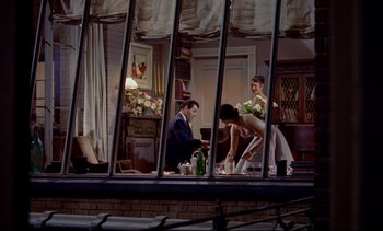 Movie still from “Rear Window” (1954), directed by Alfred Hitchcock – A group of people sitting at a table in front of a window; Wide shot, High angle