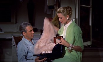 Movie still from “Rear Window” (1954), directed by Alfred Hitchcock – A man and a woman are looking at a purse; Medium shot, High angle