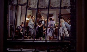 Movie still from “Rear Window” (1954), directed by Alfred Hitchcock – A group of people sitting around a table; Wide shot, High angle
