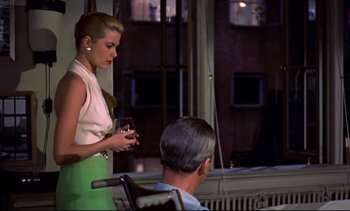 Movie still from “Rear Window” (1954), directed by Alfred Hitchcock – A woman standing next to a man in a wheelchair; Medium shot, Over the shoulder angle