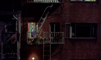Movie still from “Rear Window” (1954), directed by Alfred Hitchcock – A man standing on a fire escape looking out of a window; Extreme Wide shot, Low angle