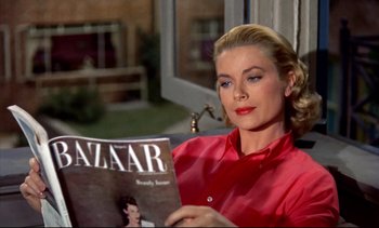 Movie still from “Rear Window” (1954), directed by Alfred Hitchcock – A woman in a red shirt is reading a magazine; Medium shot, High angle