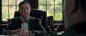 Movie still from “Richard Jewell” (2019), directed by Clint Eastwood – An older man sitting at a desk in front of a window; Close Up shot, Over the shoulder angle