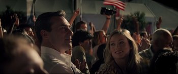 Movie still from “Richard Jewell” (2019), directed by Clint Eastwood – A group of people sitting in front of an american flag; Close Up shot, Over the shoulder angle