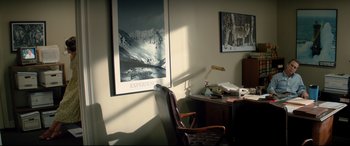 Movie still from “Richard Jewell” (2019), directed by Clint Eastwood – A chair in front of a desk with a lamp and a picture on the wall; Wide shot, High angle