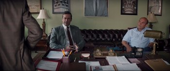 Movie still from “Richard Jewell” (2019), directed by Clint Eastwood – A man sitting at a table in front of papers and pencils; Medium shot, Over the shoulder angle