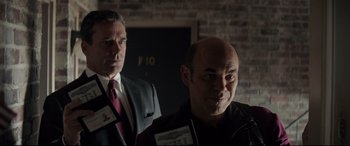 Movie still from “Richard Jewell” (2019), directed by Clint Eastwood – Two men in suits and ties standing next to each other; Medium shot, Over the shoulder angle