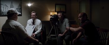 Movie still from “Richard Jewell” (2019), directed by Clint Eastwood – A group of people sitting around a camera; Medium shot, Over the shoulder angle