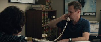 Movie still from “Richard Jewell” (2019), directed by Clint Eastwood – A man sitting at a desk talking on a phone; Medium shot, High angle