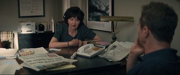 Movie still from “Richard Jewell” (2019), directed by Clint Eastwood – A woman sitting at a table with a newspaper; Medium shot, Over the shoulder angle