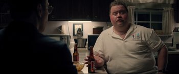 Movie still from “Richard Jewell” (2019), directed by Clint Eastwood – A man sitting at a table with two beer bottles; Medium shot, Over the shoulder angle