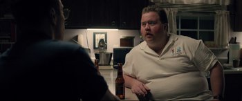 Movie still from “Richard Jewell” (2019), directed by Clint Eastwood – A man sitting at a table with a bottle of beer in front of him; Medium shot, Over the shoulder angle