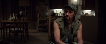 Movie still from “Richard Jewell” (2019), directed by Clint Eastwood – A man sitting in a chair wearing a hat; Medium shot, Over the shoulder angle