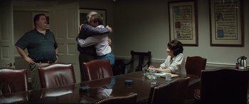 Movie still from “Richard Jewell” (2019), directed by Clint Eastwood – Two men hugging in front of a table with two women sitting at the table; Medium shot, Over the shoulder angle