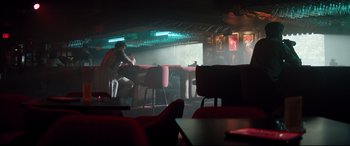 Movie still from “Richard Jewell” (2019), directed by Clint Eastwood – Two people sitting at a table in front of a bar; Wide shot, Low angle