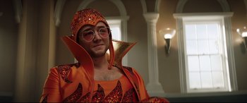 Movie still from “Rocketman” (2019), directed by Dexter Fletcher – A man in a costume is posing for a picture; Close Up shot, Low angle
