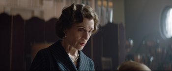 Movie still from “Rocketman” (2019), directed by Dexter Fletcher – An older woman wearing a suit and pearl necklace; Close Up shot, Over the shoulder angle