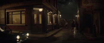 Movie still from “Rocketman” (2019), directed by Dexter Fletcher – People walking down the street in front of a building; Extreme Wide shot, High angle