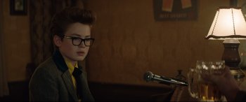 Movie still from “Rocketman” (2019), directed by Dexter Fletcher – A young boy wearing glasses and a tie; Close Up shot, Over the shoulder angle