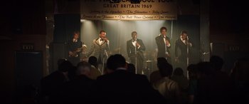 Movie still from “Rocketman” (2019), directed by Dexter Fletcher – A group of men singing in front of an audience; Wide shot, High angle