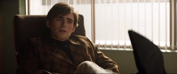 Movie still from “Rocketman” (2019), directed by Dexter Fletcher – A man sitting in a chair in front of a window; Medium shot, Over the shoulder angle