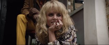 Movie still from “Rocketman” (2019), directed by Dexter Fletcher – A woman with blonde curly hair wearing a ring; Close Up shot, Over the shoulder angle