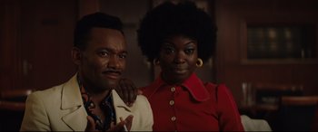 Movie still from “Rocketman” (2019), directed by Dexter Fletcher – A man and a woman pose for a picture; Close Up shot, Low angle