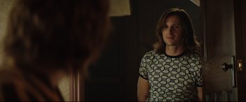 Movie still from “Rocketman” (2019), directed by Dexter Fletcher – A woman in a black and white shirt looking at a mirror; Medium shot, Over the shoulder angle