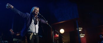 Movie still from “Rocketman” (2019), directed by Dexter Fletcher – A man standing on a stage holding a microphone; Medium shot, Low angle