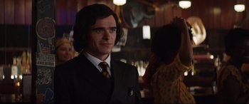 Movie still from “Rocketman” (2019), directed by Dexter Fletcher – A man wearing a suit and tie in a room; Close Up shot, Over the shoulder angle