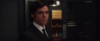 Movie still from “Rocketman” (2019), directed by Dexter Fletcher – A man wearing a suit and tie standing in a room; Close Up shot, Over the shoulder angle